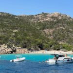 Breathtaking view of a serene beach in Sardinia, Italy, featuring boats and clear turquoise waters.